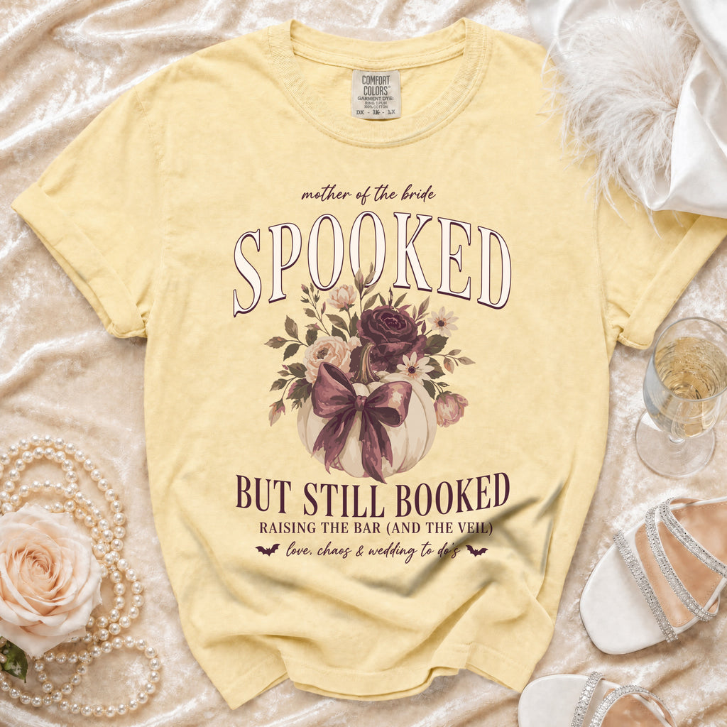 Yellow t-shirt with "Spooked but still booked" text, pumpkin, and floral graphics.