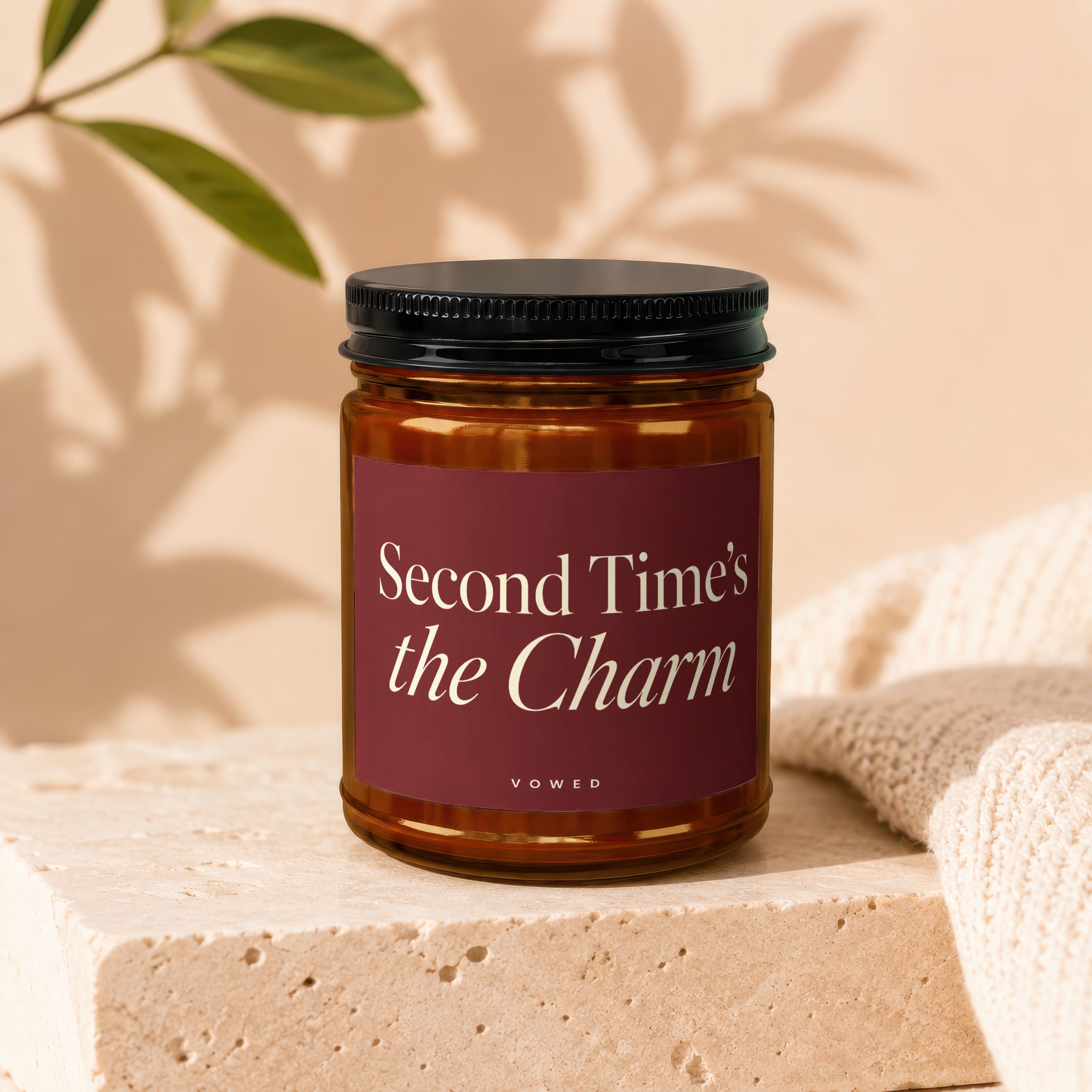Amber glass candle with black lid labeled "Second Time's the Charm" by VOWED.
