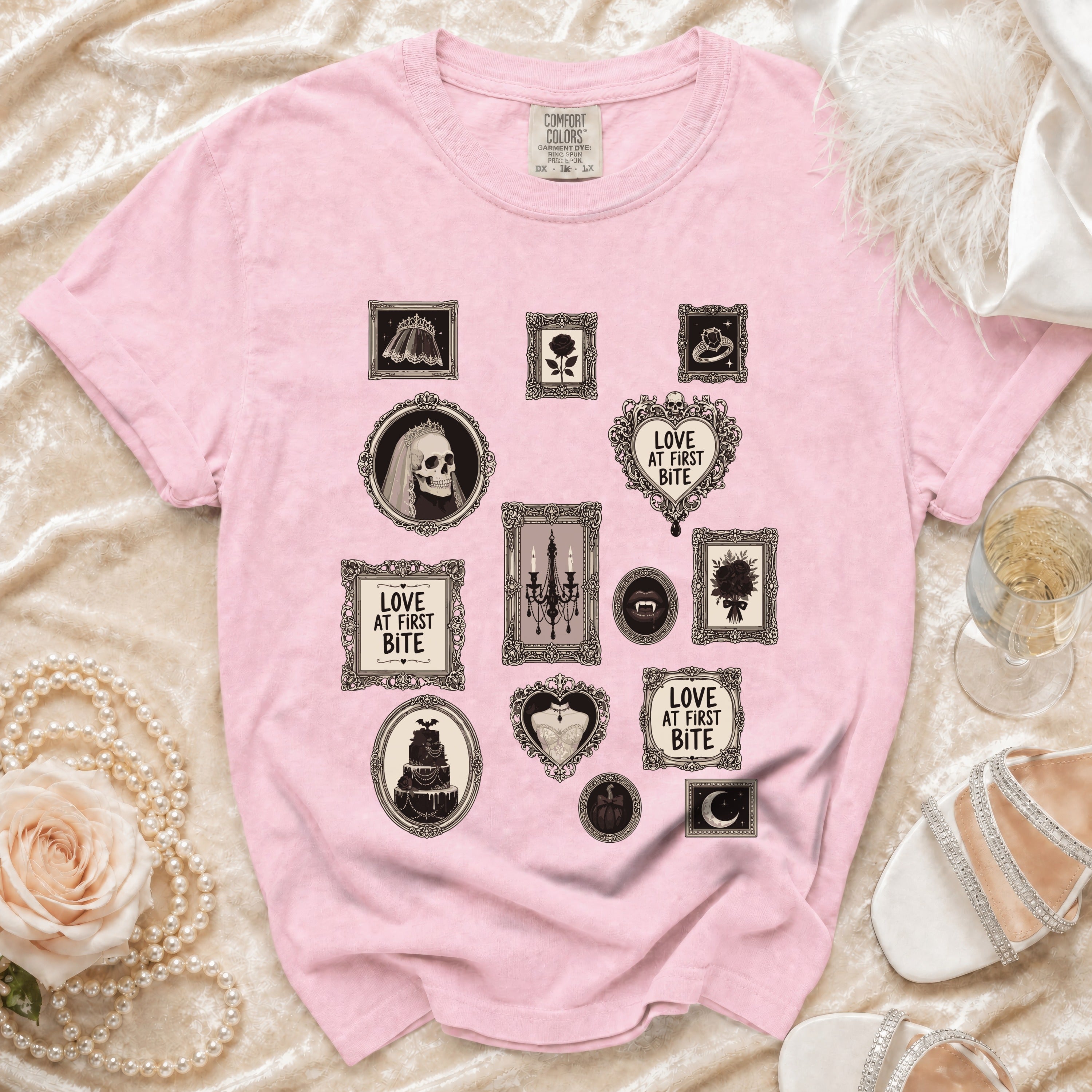 Pink t-shirt with framed gothic-themed prints including a skull, cake, and text.