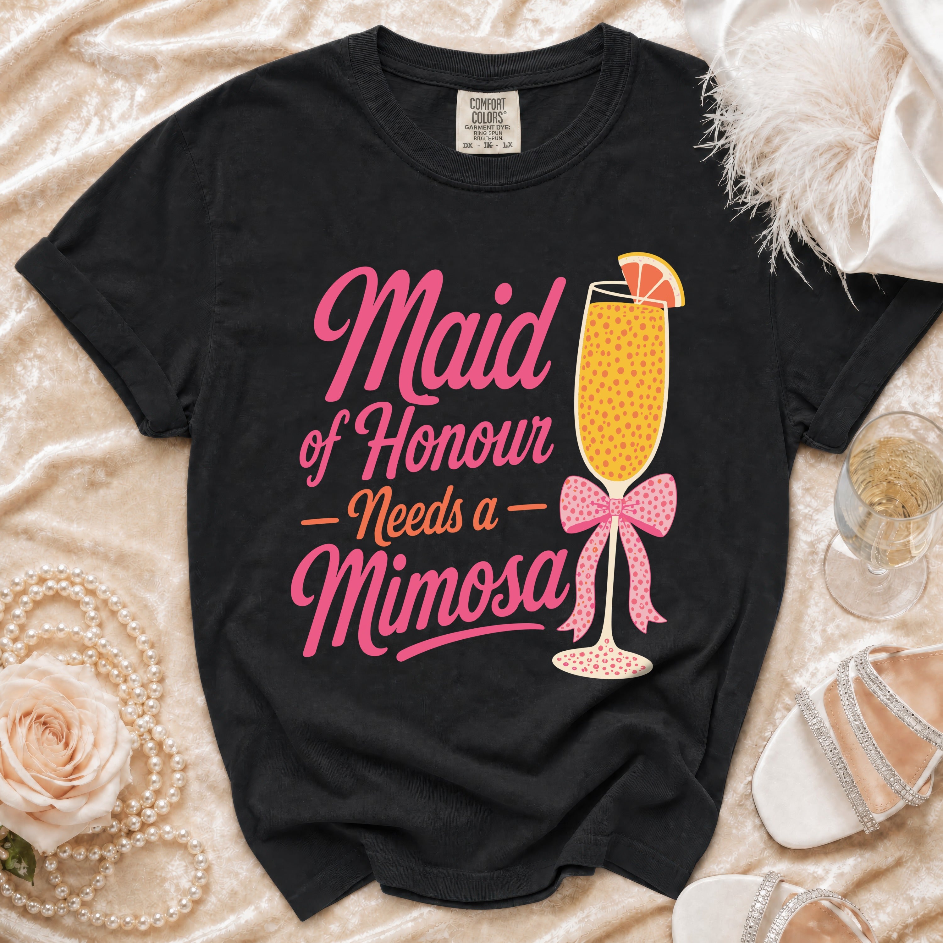 Black t-shirt with "Maid of Honour Needs a Mimosa" text and a mimosa glass graphic.