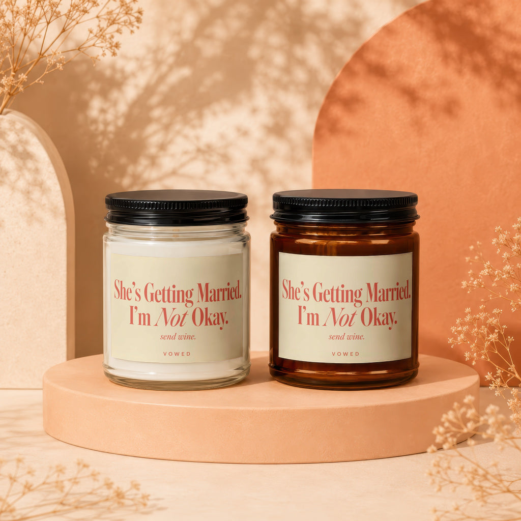 Two candles with labels reading "She's Getting Married. I'm Not Okay. send wine."