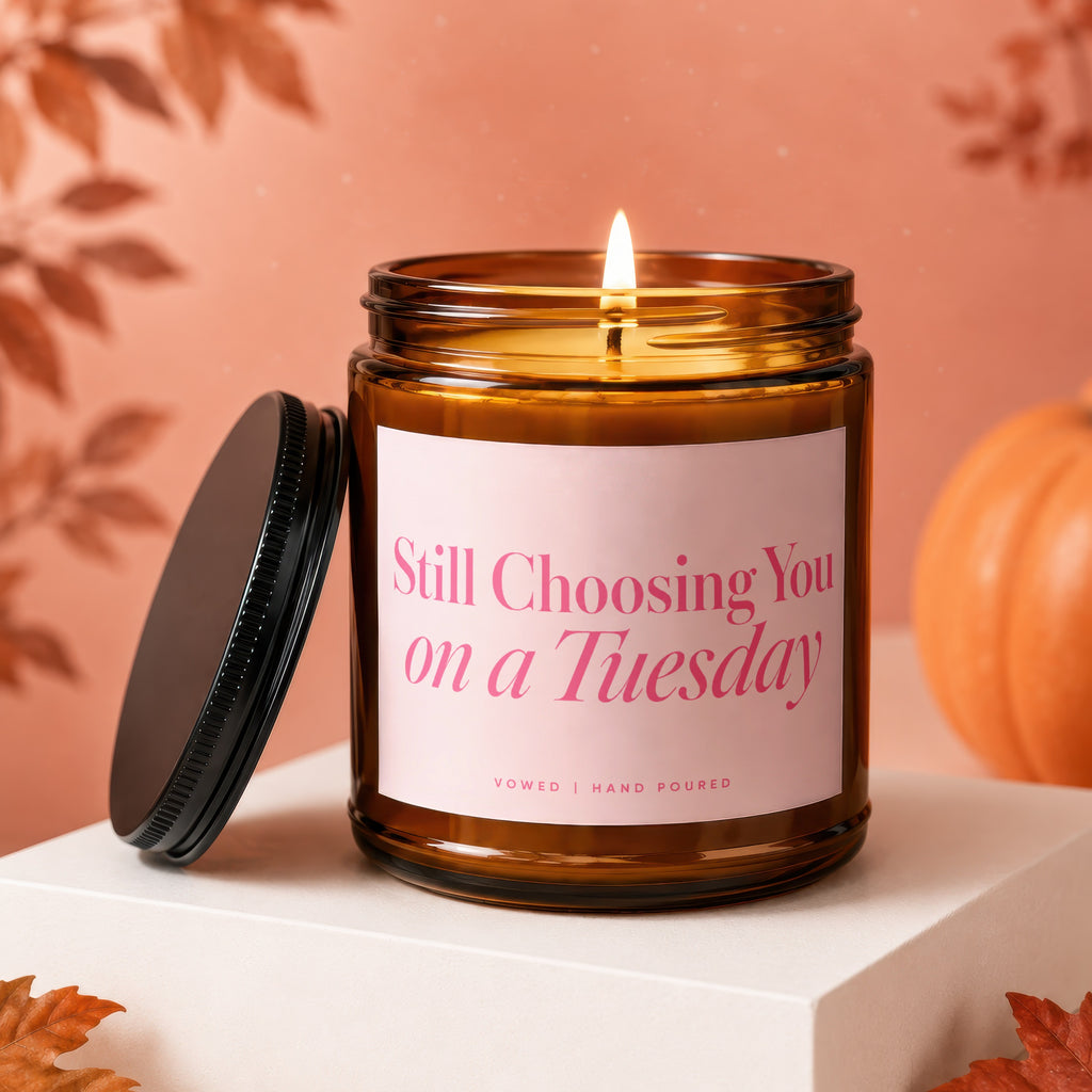 Amber glass candle with a pink label reading "Still Choosing You on a Tuesday".