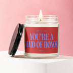 Candle with red label saying "Smells Like You're A Maid of Honor".