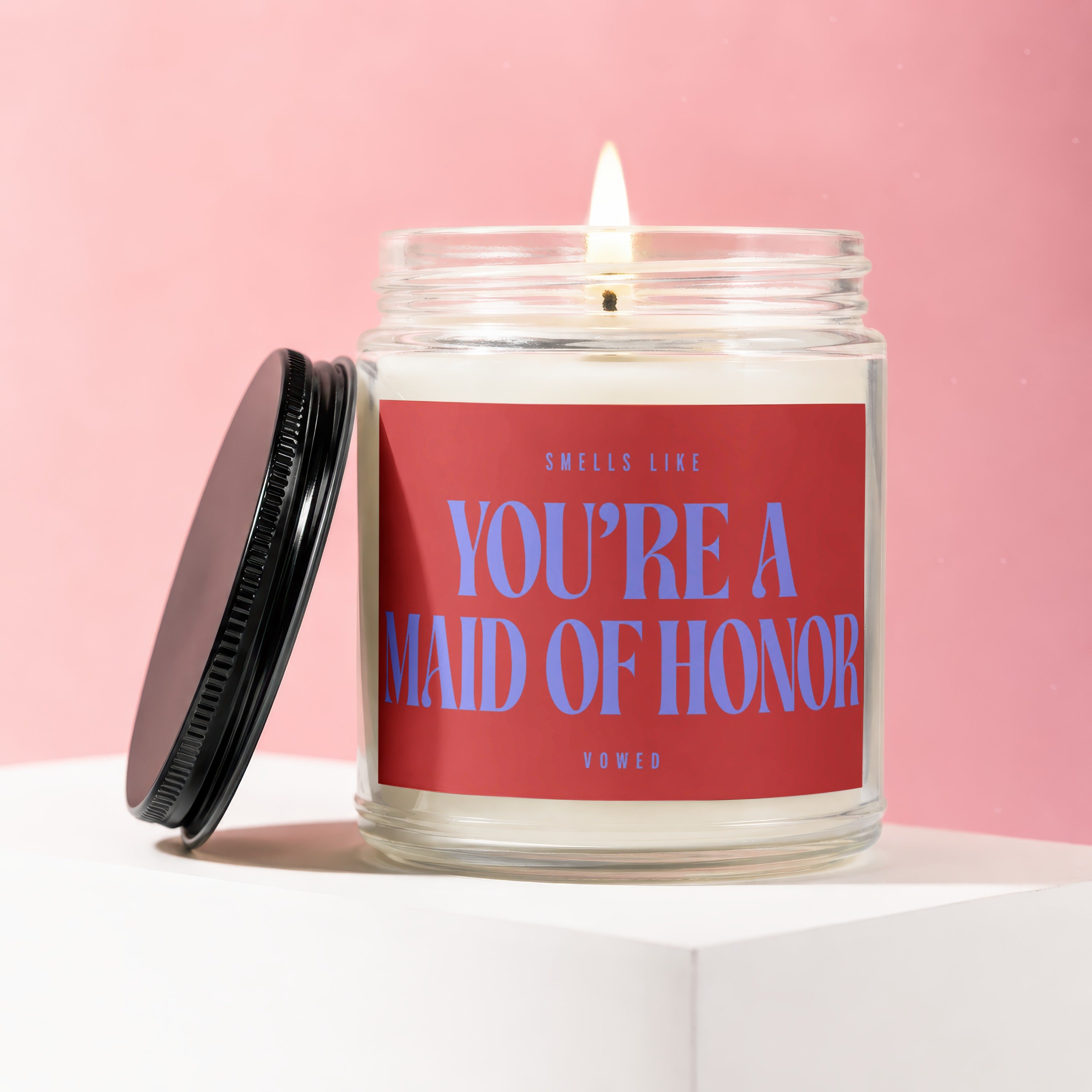 Candle with red label saying "Smells Like You're A Maid of Honor".