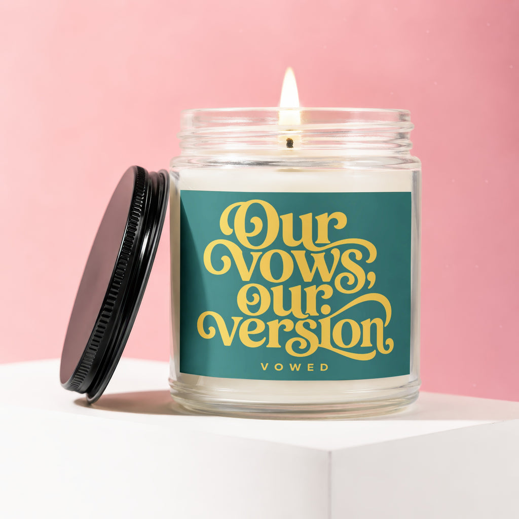 Candle with teal label reading "Our vows, our version, vowed" in yellow script.