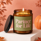 Amber jar candle with "Partner for Life VOWED" text on green label