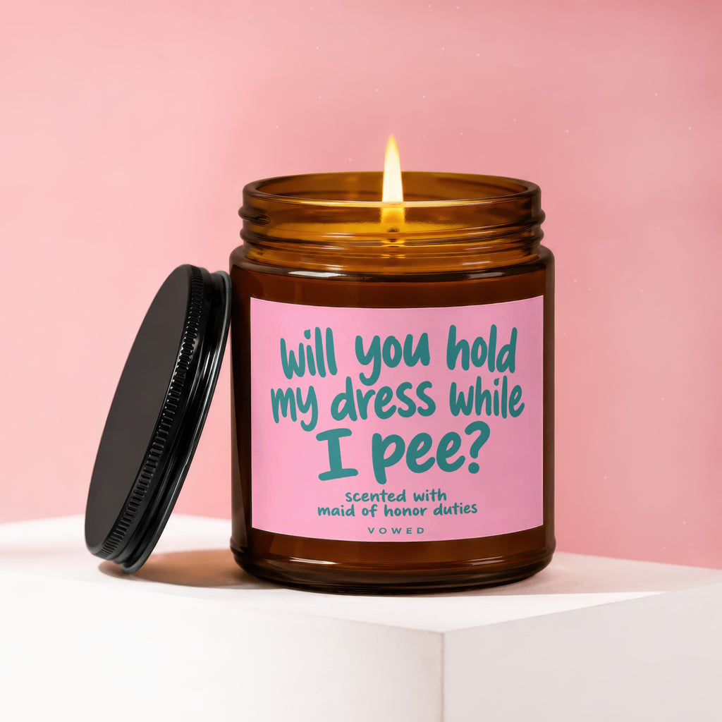 Amber jar candle with pink label asking "will you hold my dress while I pee?".