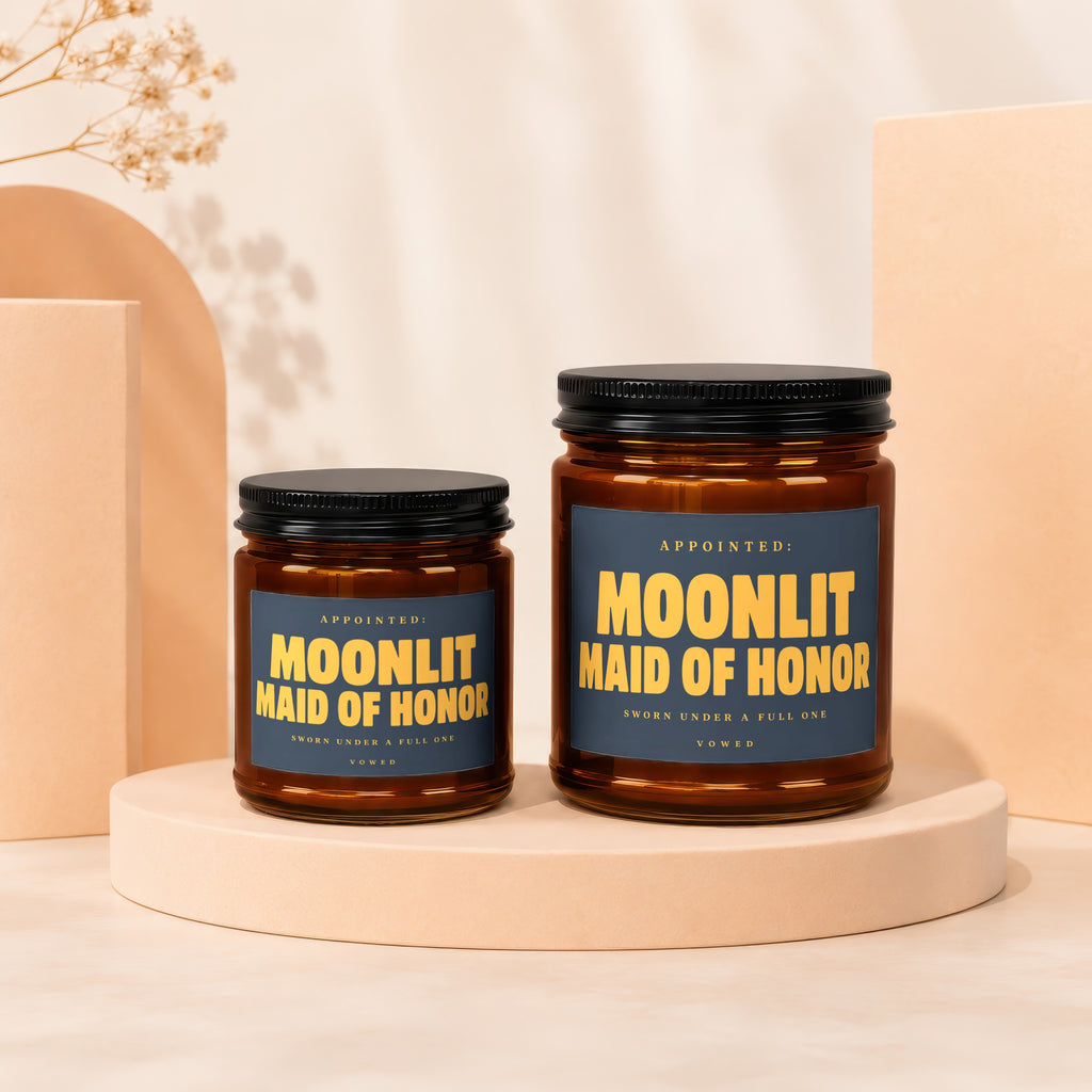Two amber glass candles labeled "Moonlit Maid of Honor" on pedestals.