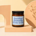 Amber glass candle with "Certified Bridezilla Bride-to-Be" label on pedestal.