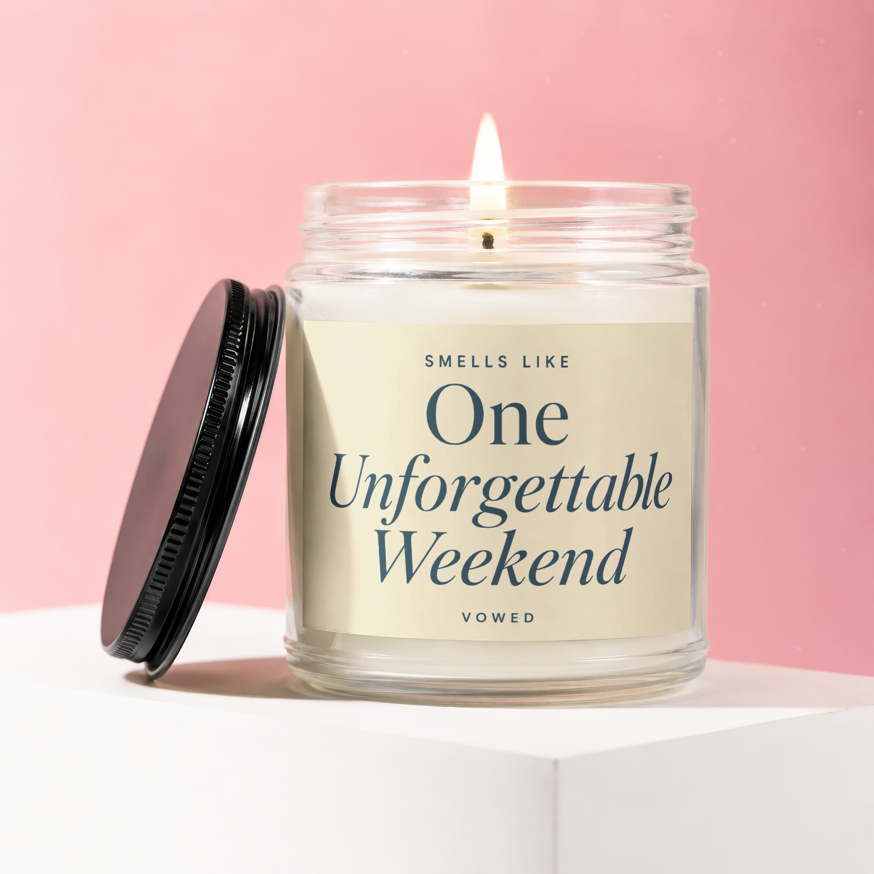 Candle labeled "Smells Like One Unforgettable Weekend," with a lit wick.