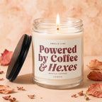 Lit candle in glass jar with label "Smells like Powered by Coffee & Hexes".