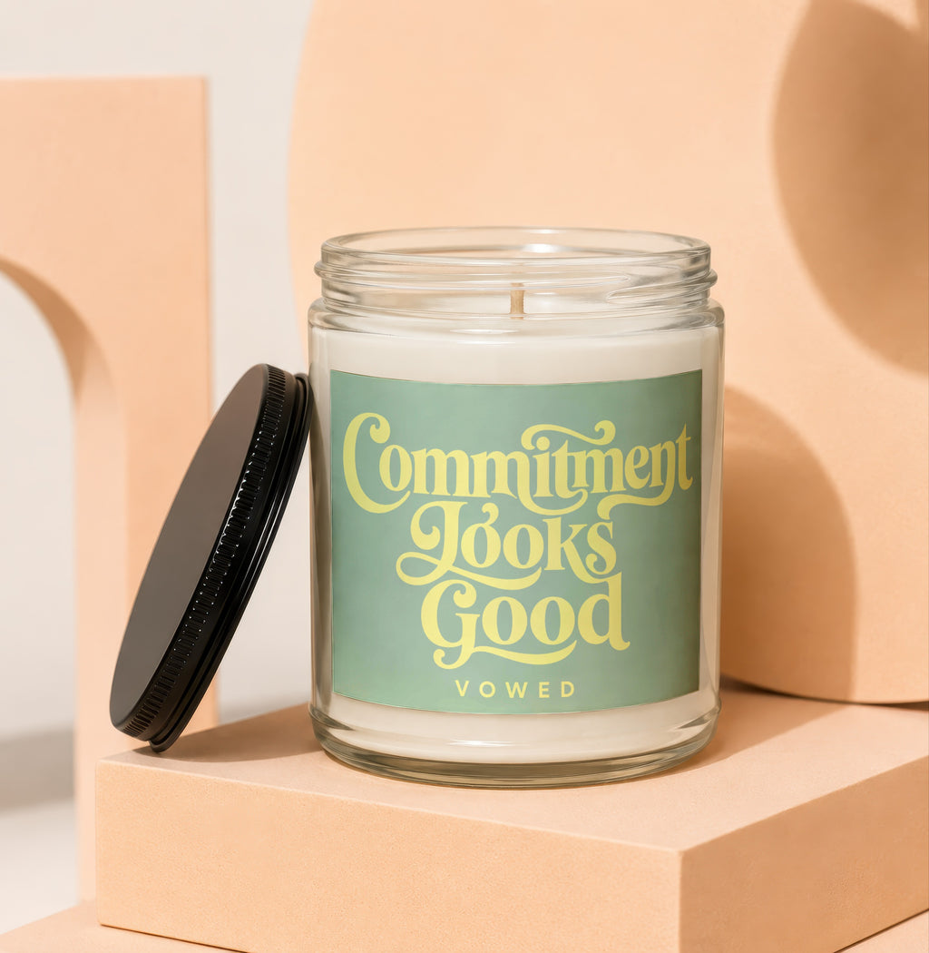 Glass candle with green label that reads "Commitment Looks Good VOWED".