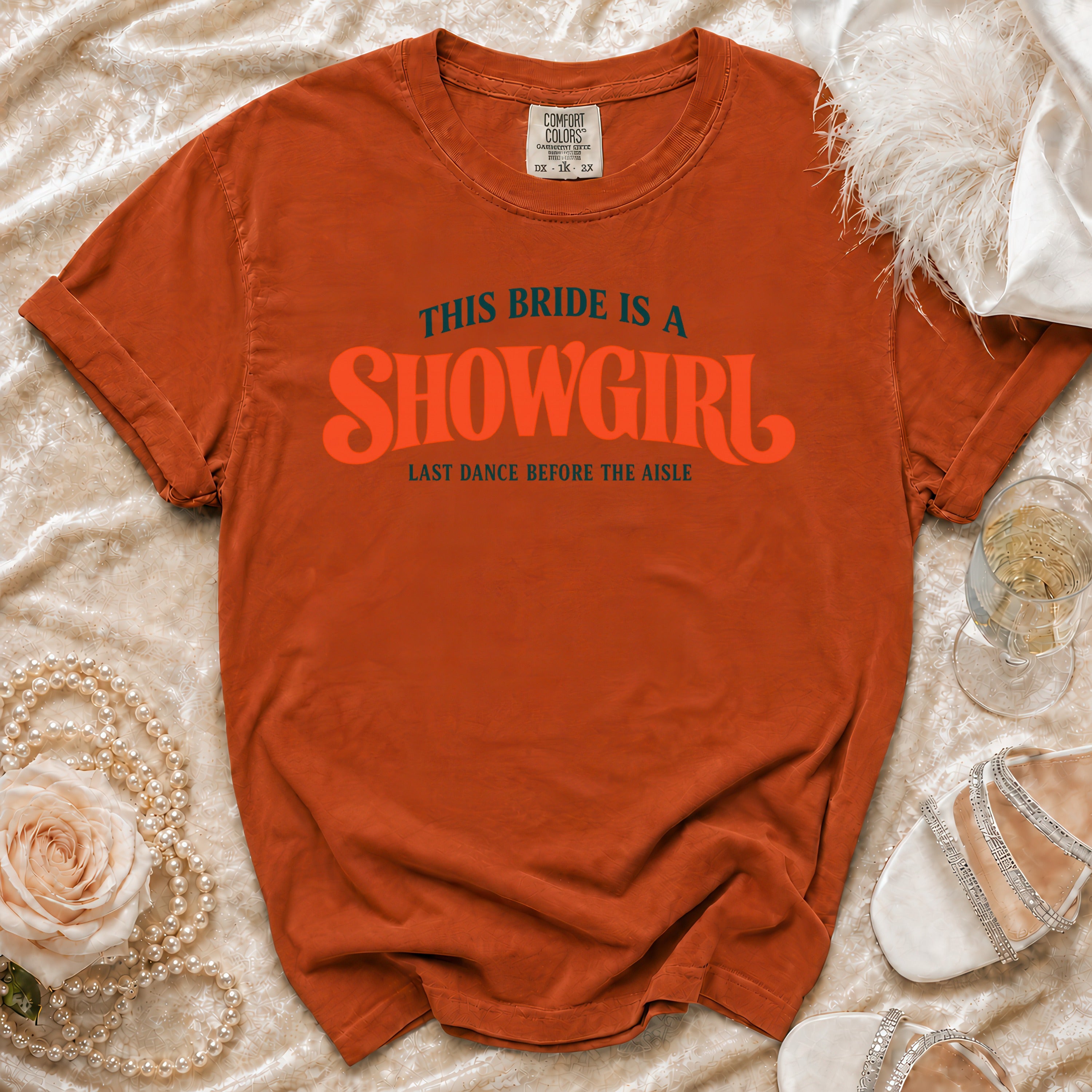 Orange t-shirt with "This Bride is a Showgirl" graphic and wedding accessories.