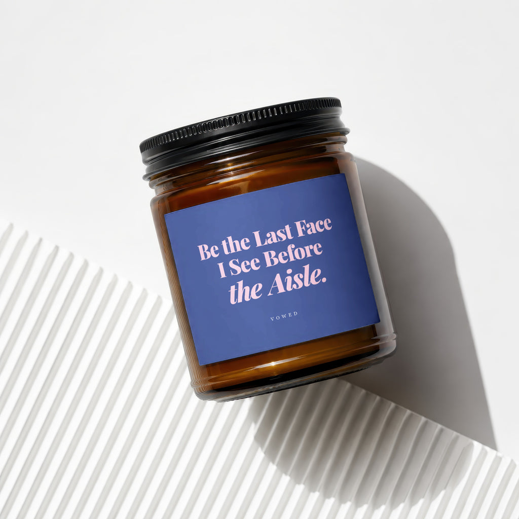 Amber jar candle with blue label reading "Be the Last Face I See Before the Aisle."