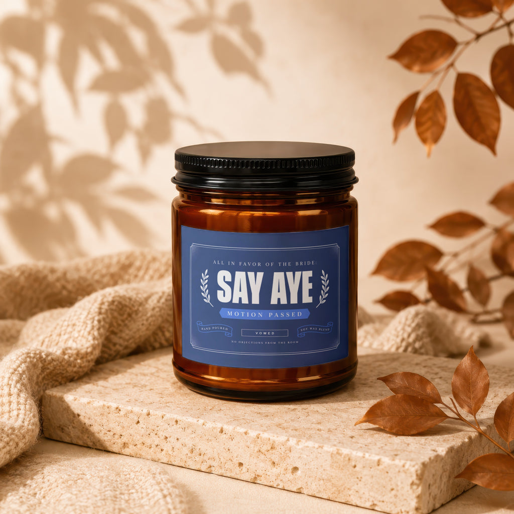 Amber jar candle with "Say Aye Motion Passed Vowed" label, on a stone block.