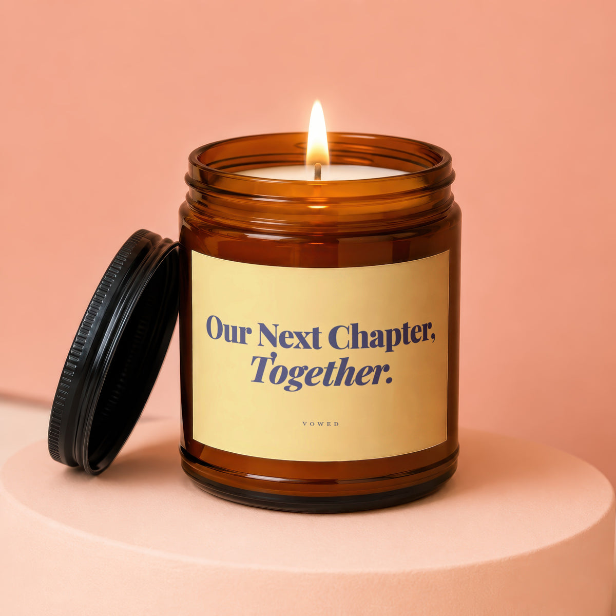 Amber jar candle with lit flame and lid. Text reads "Our Next Chapter, Together."