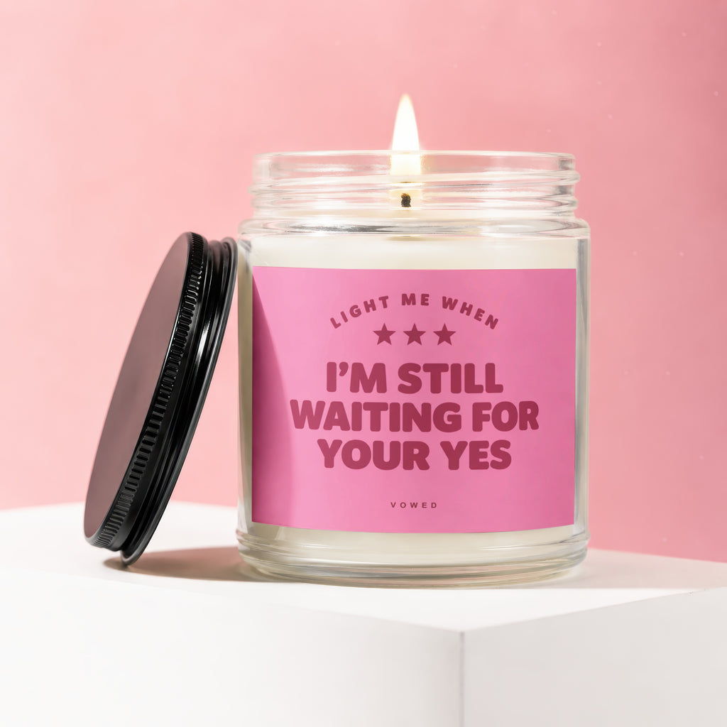 Candle with pink label saying "Light me when I'm still waiting for your yes".
