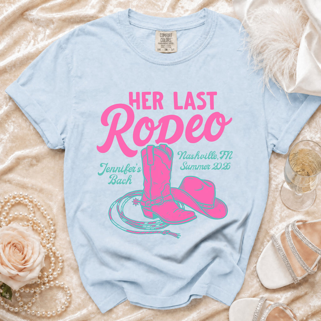 Light blue t-shirt with pink text and graphics for "Her Last Rodeo".
