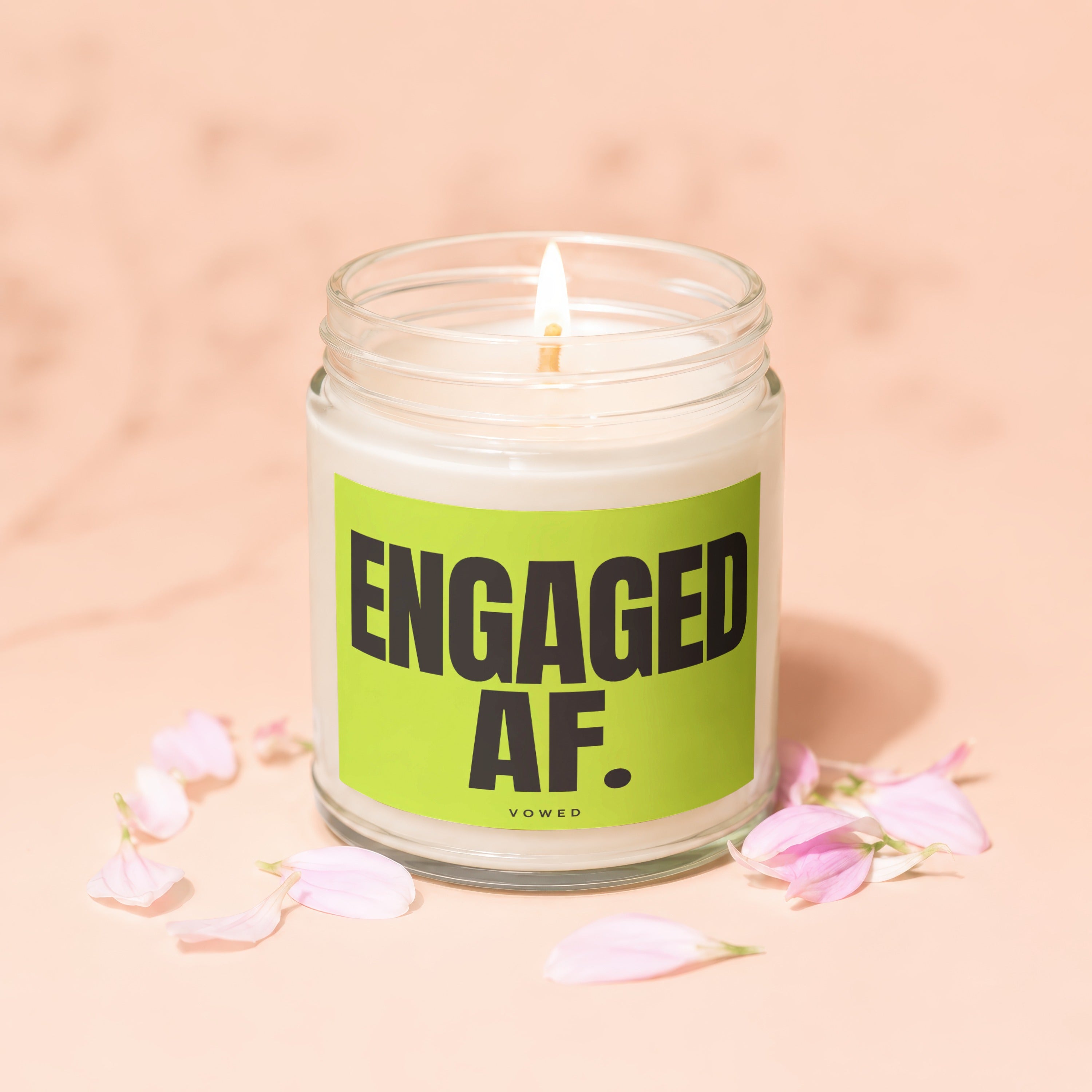 Engaged AF. candle in a glass jar with a lit wick and pink petals.