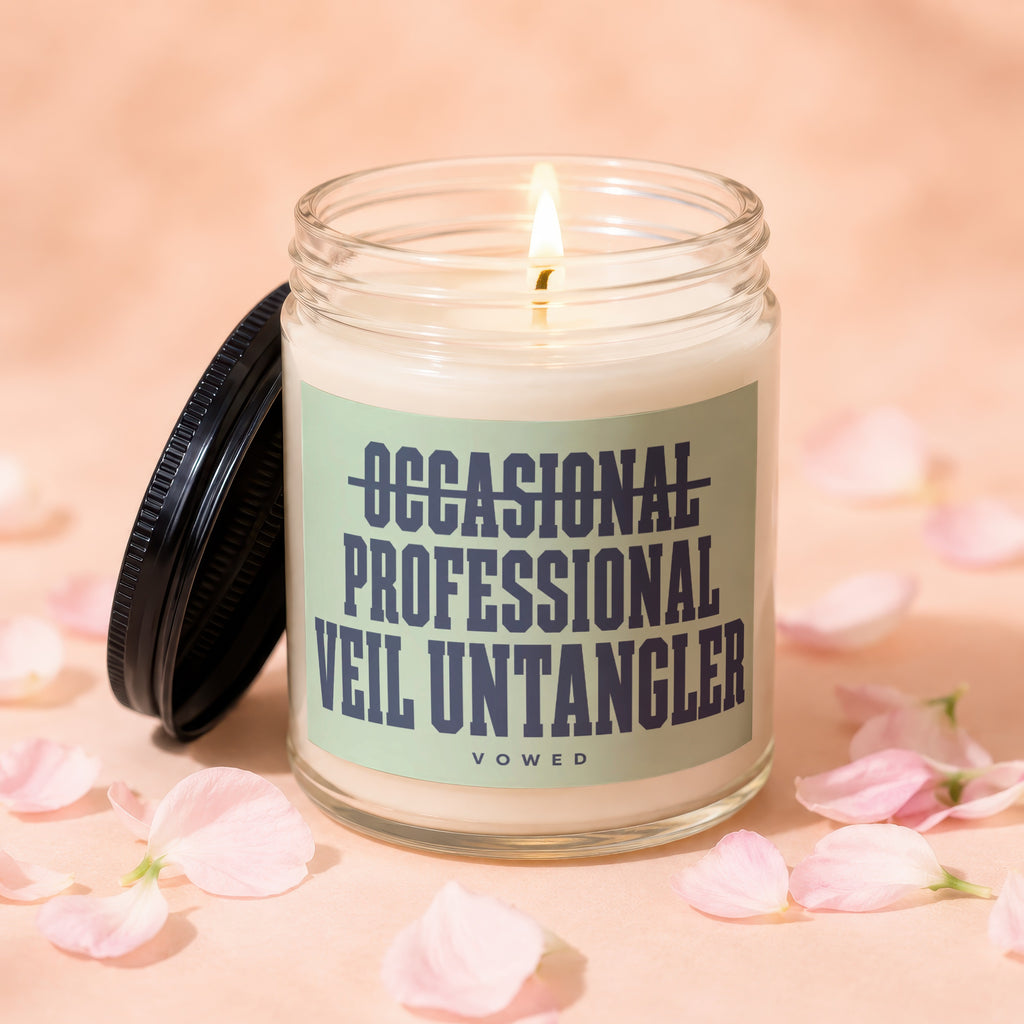 Glass jar candle with lit wick, labeled "OCCASIONAL PROFESSIONAL VEIL UNTANGLER" and "VOWED".