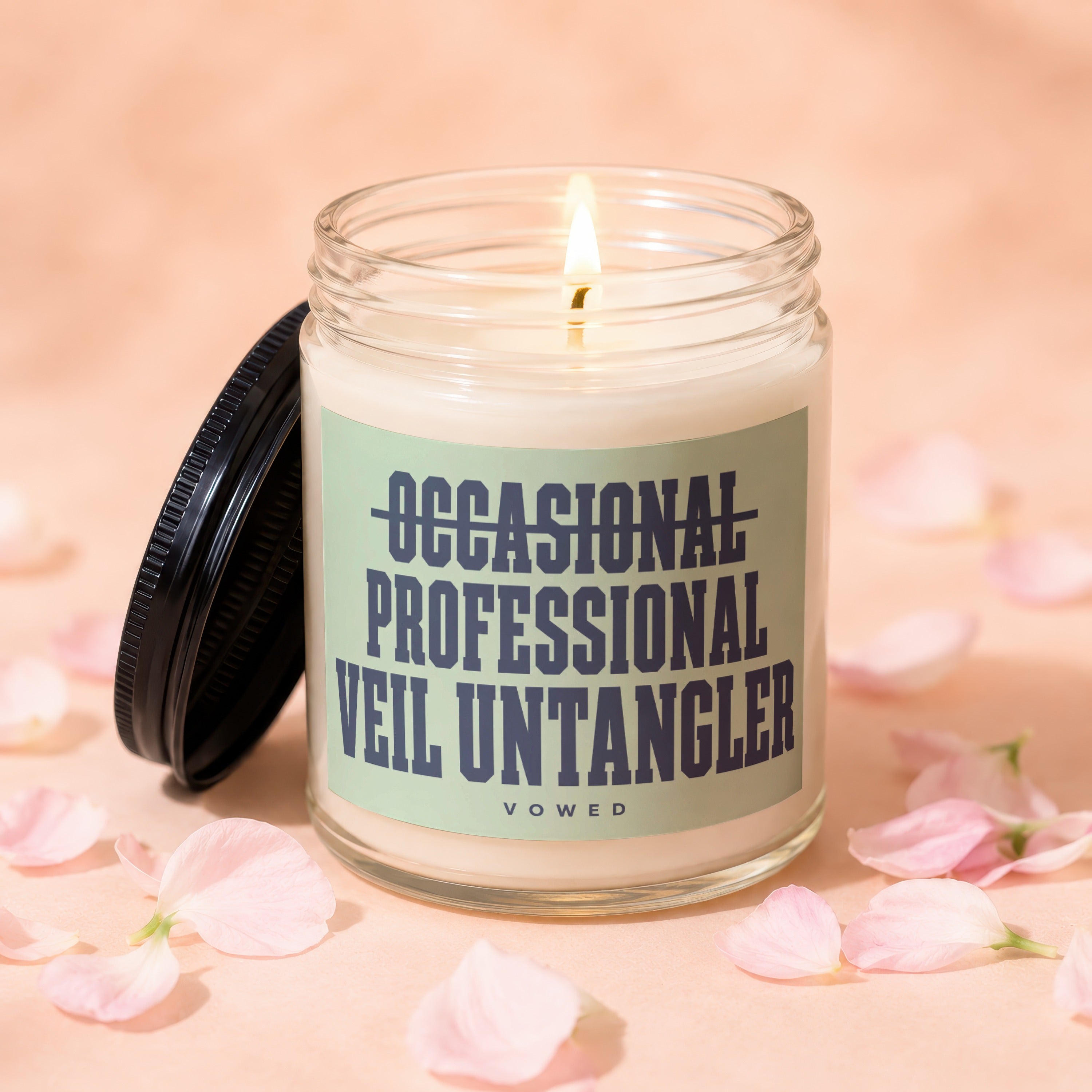 Glass jar candle with lit wick, labeled "OCCASIONAL PROFESSIONAL VEIL UNTANGLER" and "VOWED".