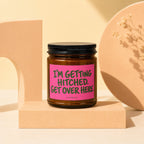 Brown glass candle with pink label reading "I'm Getting Hitched. Get Over Here."