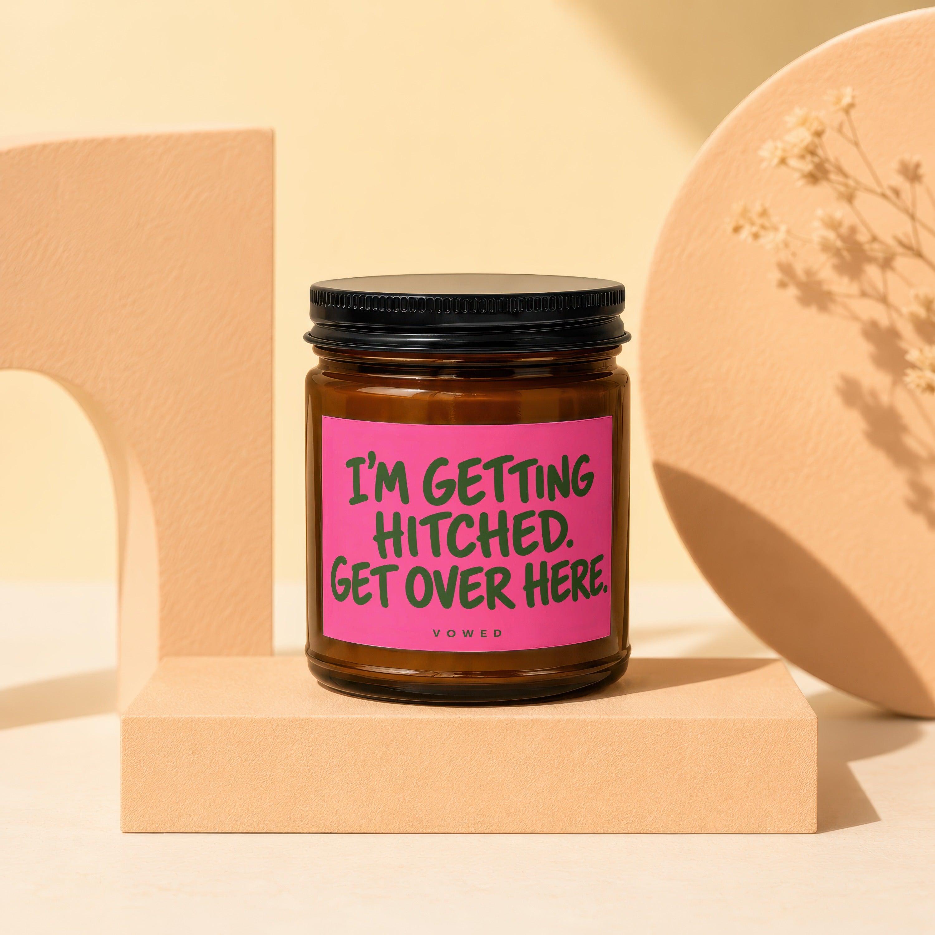 Brown glass candle with pink label reading "I'm Getting Hitched. Get Over Here."