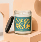 Glass candle with "Say gay Say I do" text in yellow on teal label.