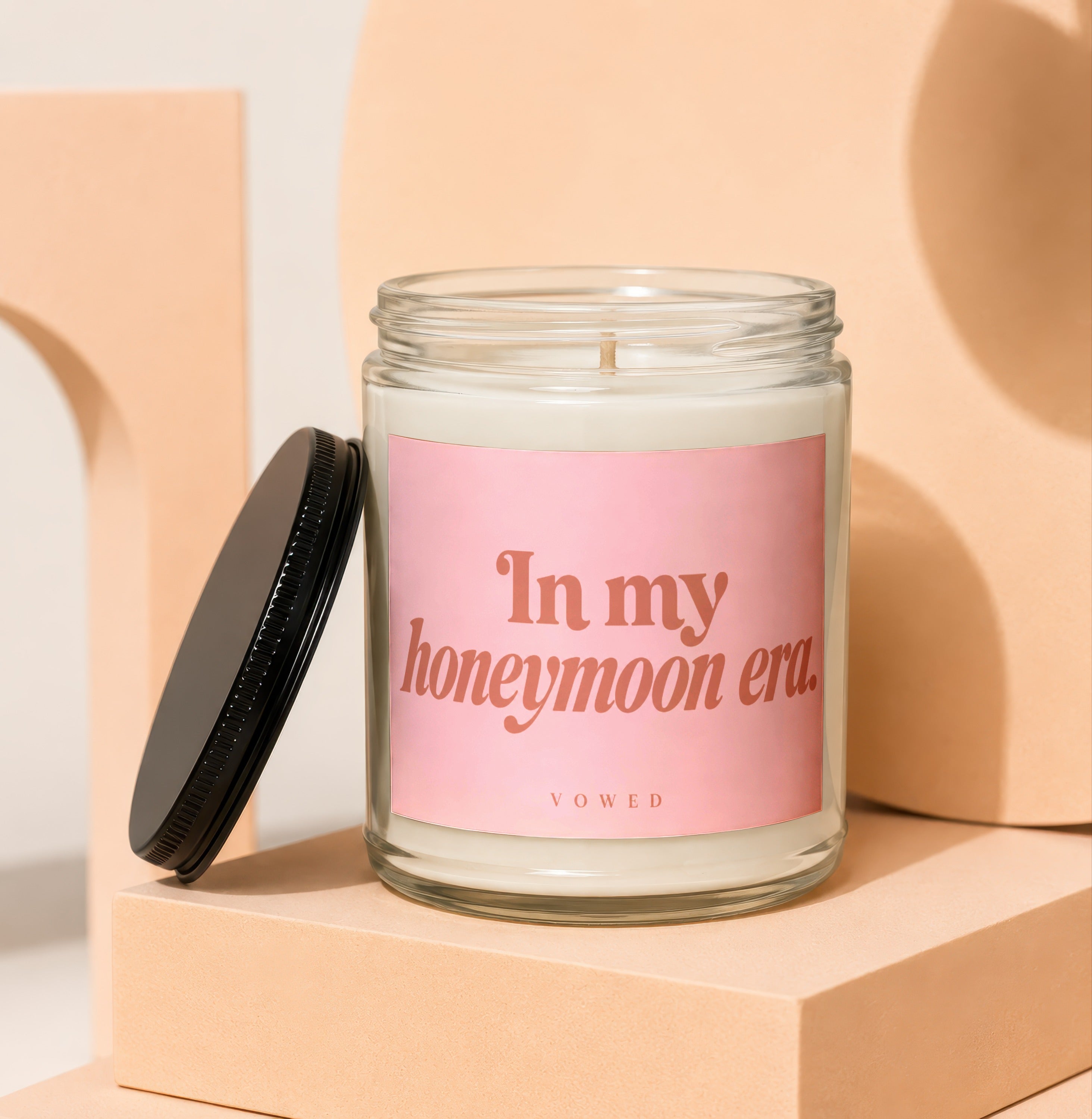 Glass candle with pink label reading "In my honeymoon era. VOWED."