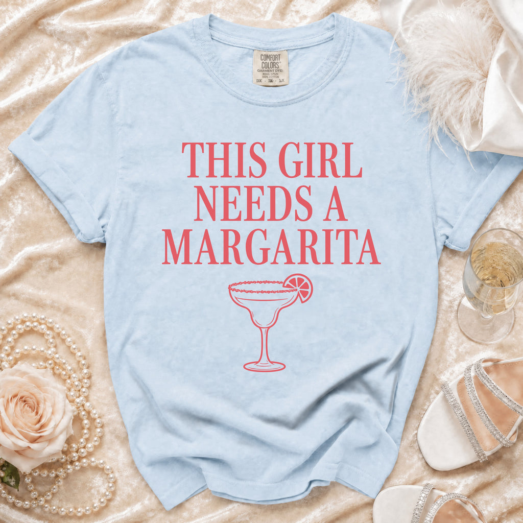 Light blue t-shirt with coral text reading "THIS GIRL NEEDS A MARGARITA" and margarita graphic.