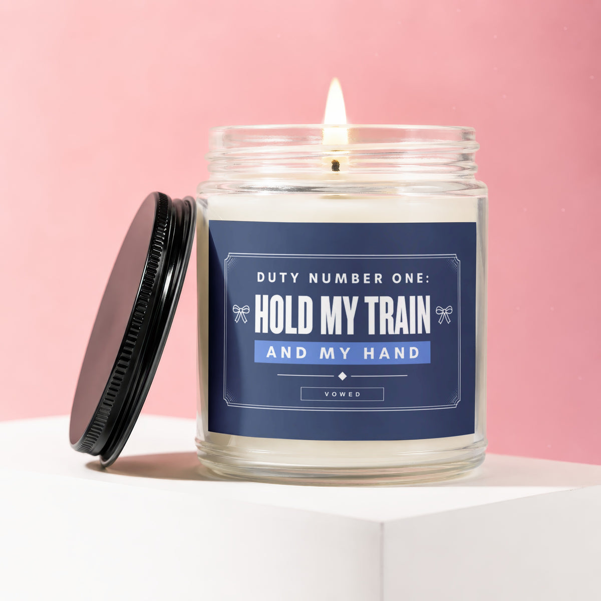 Lit candle in a jar with lid askew, text says "Hold My Train And My Hand".