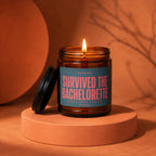 Amber jar candle with a lit flame, bearing text "Survived the Bachelorette".