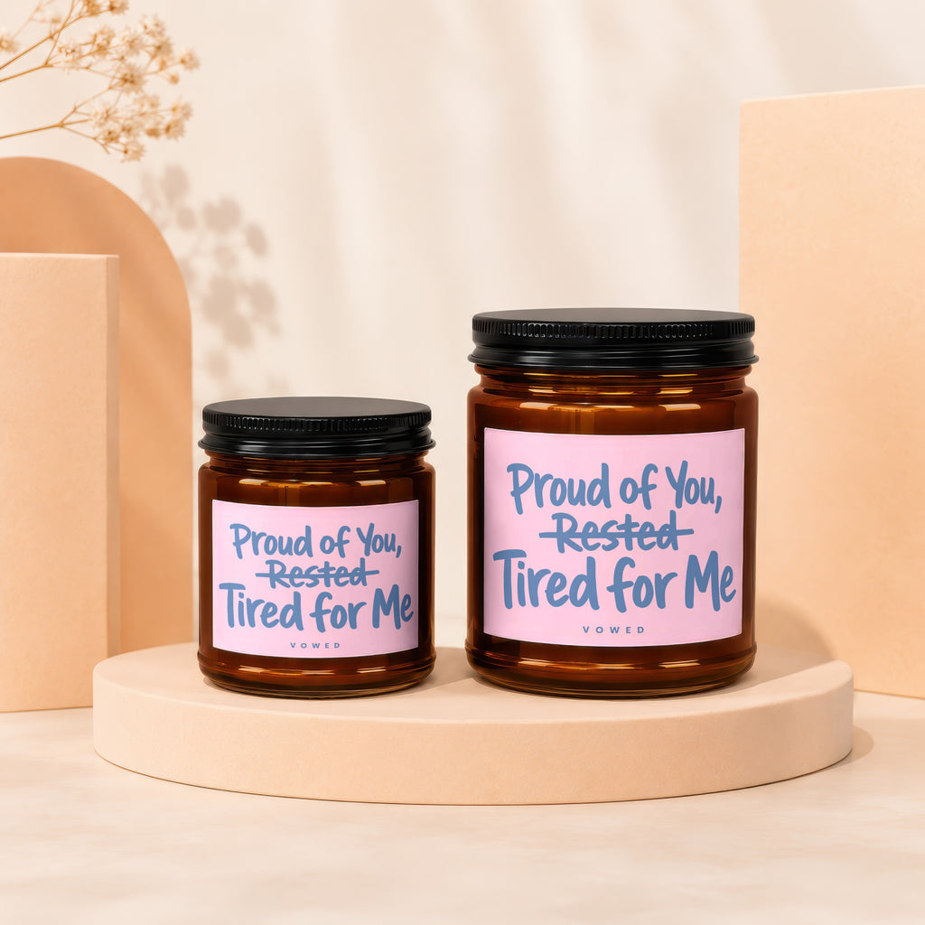 Two amber glass candles with black lids, featuring pink labels with blue text.