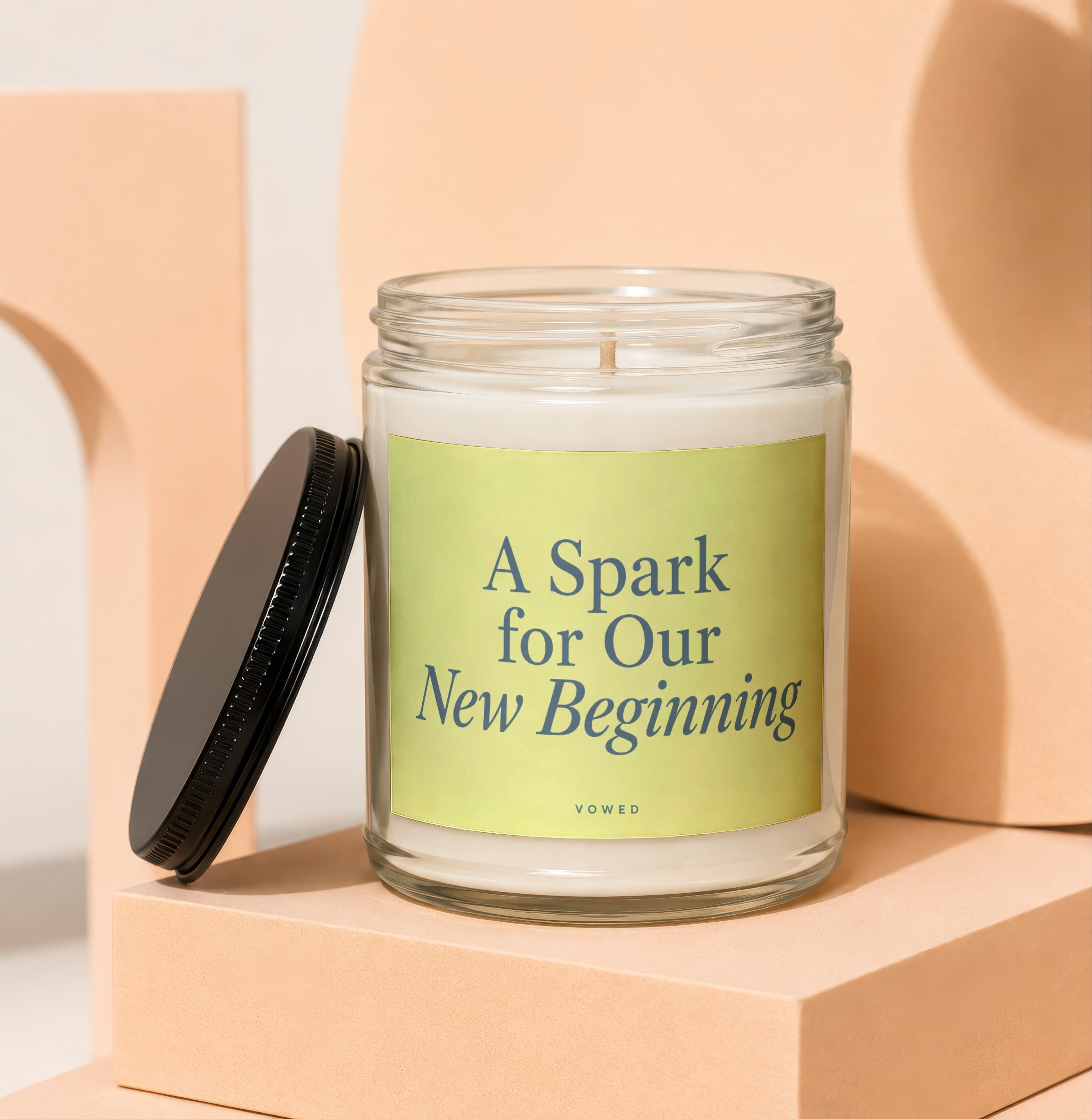Glass jar candle with "A Spark for Our New Beginning" text.