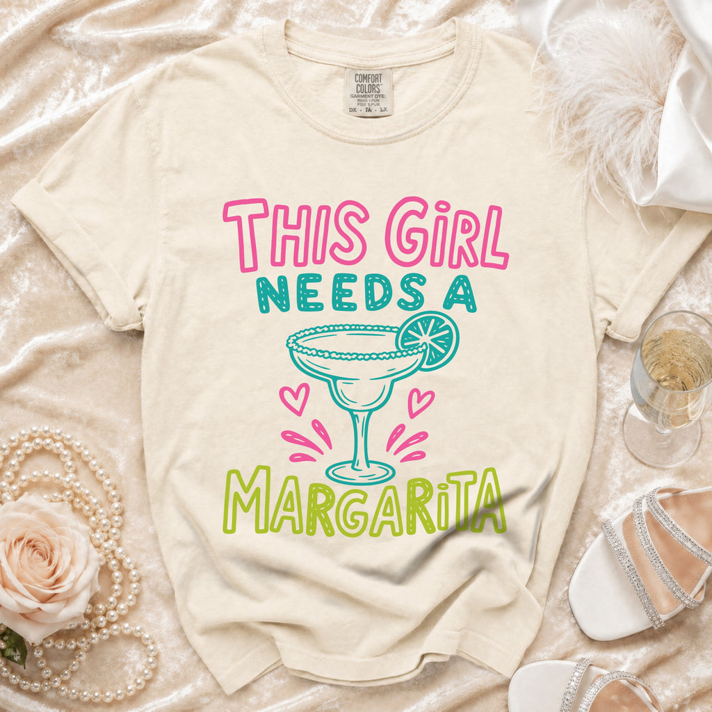 Cream t-shirt with "This Girl Needs A Margarita" text and margarita graphic.