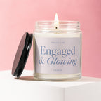 Candle with "Engaged & Glowing" text on label, lid off, on a white surface.
