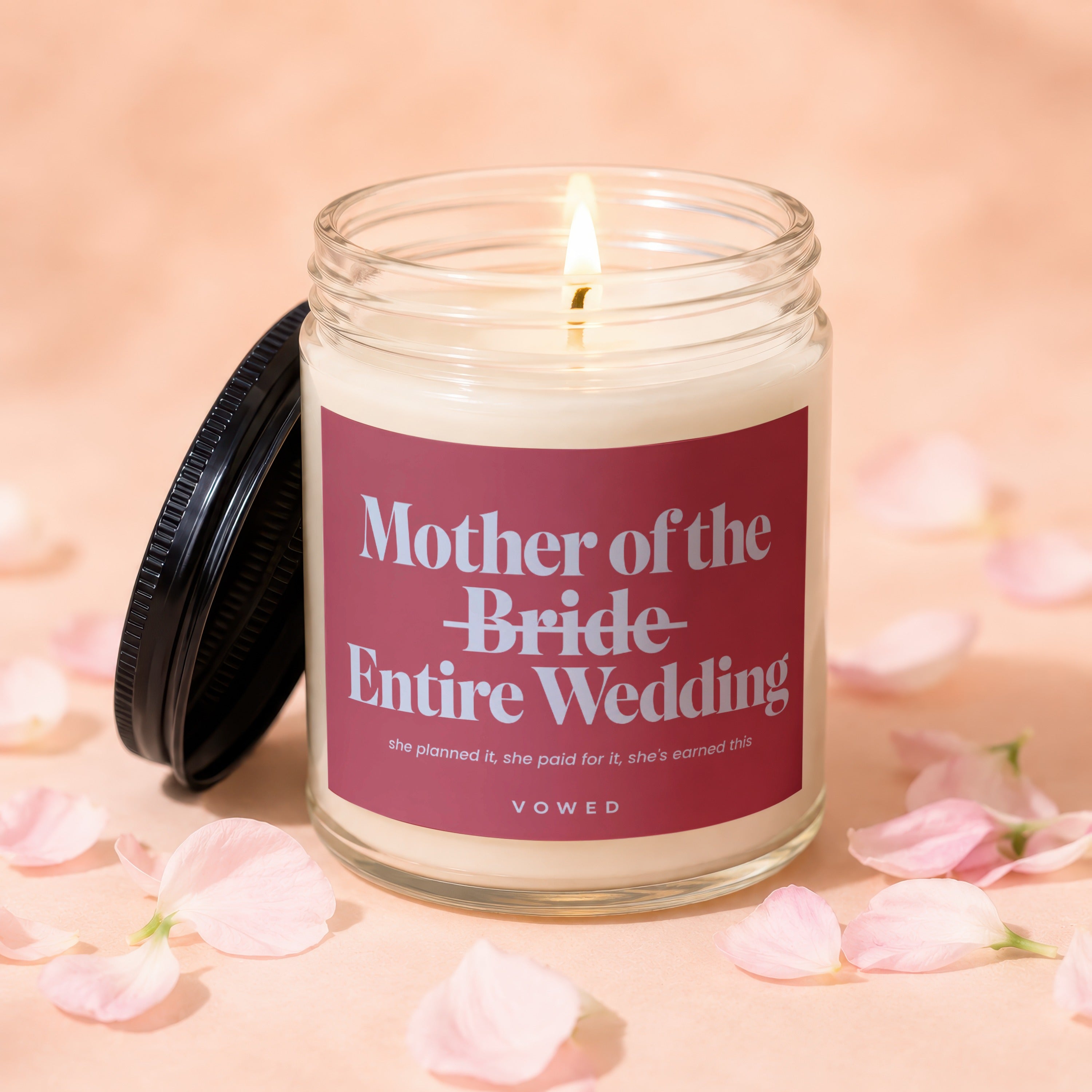 Lit candle in jar with "Mother of the Bride Entire Wedding" label, surrounded by petals.