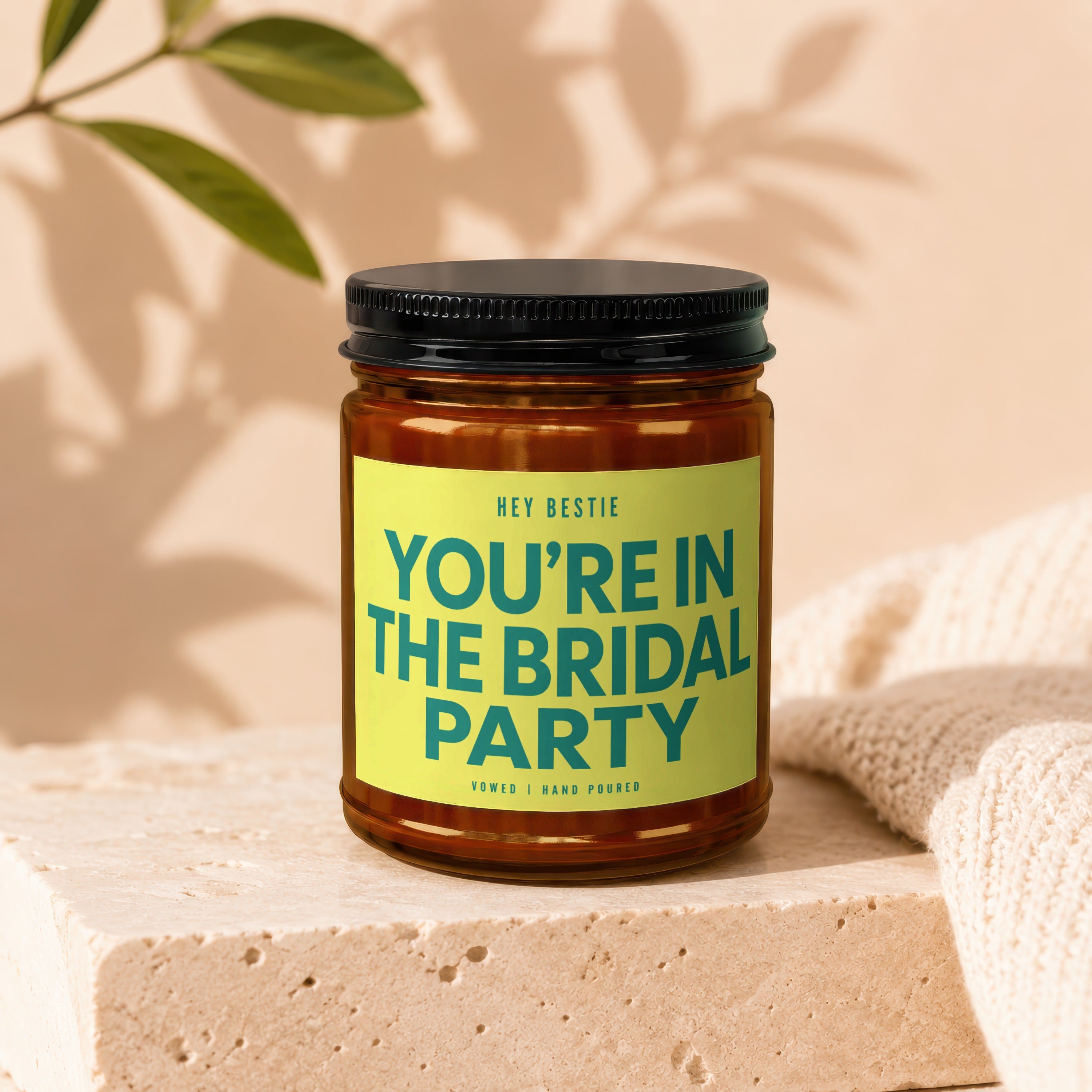 Glass candle with black lid, yellow label reading "HEY BESTIE YOU'RE IN THE BRIDAL PARTY".