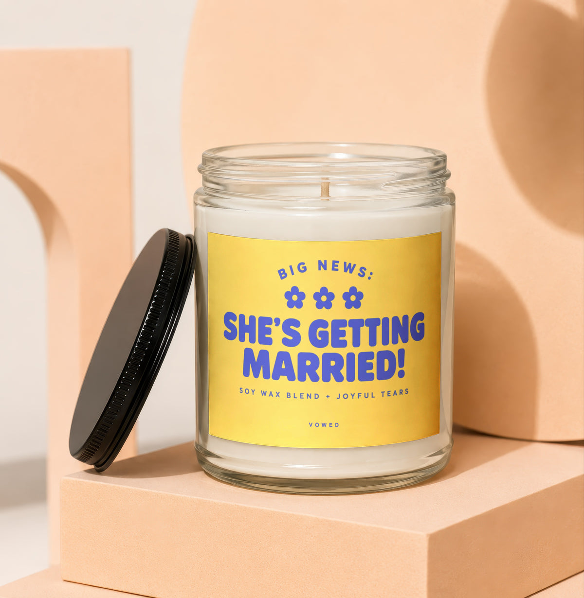Glass candle with yellow label reading "BIG NEWS: SHE'S GETTING MARRIED!".