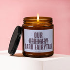 Lit candle in amber jar with dark lid, reads "Our Ordinary Dark Fairytale".
