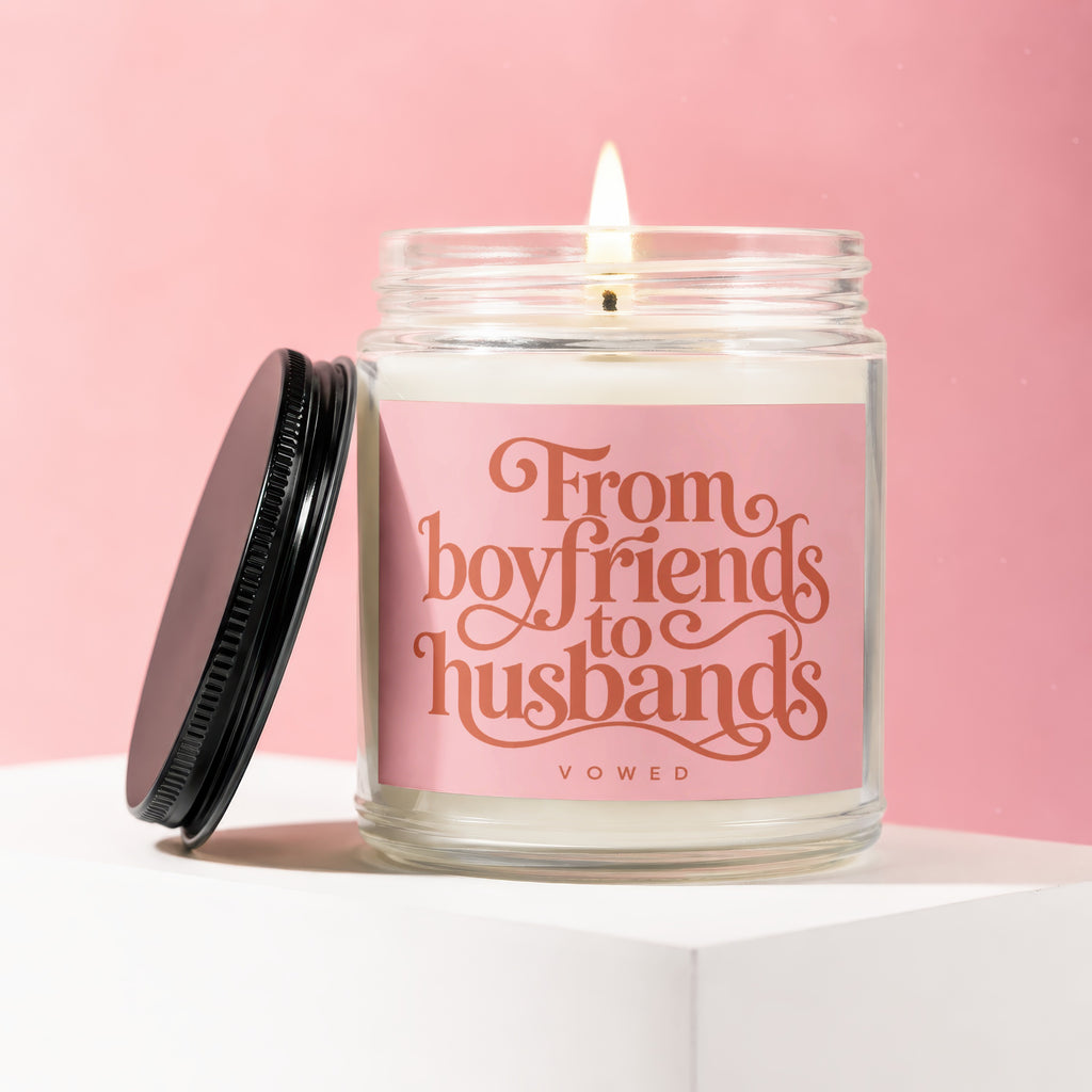 Jar candle with lit flame, reads "From boyfriends to husbands" on a pink label.
