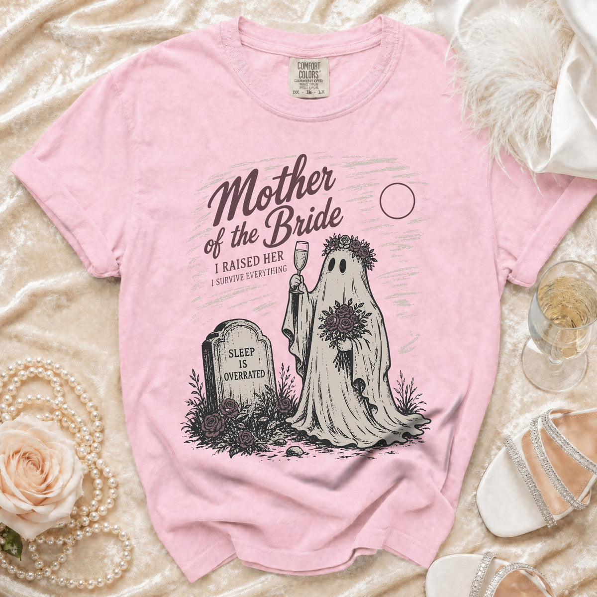 Pink t-shirt with "Mother of the Bride" ghost graphic holding champagne and flowers.