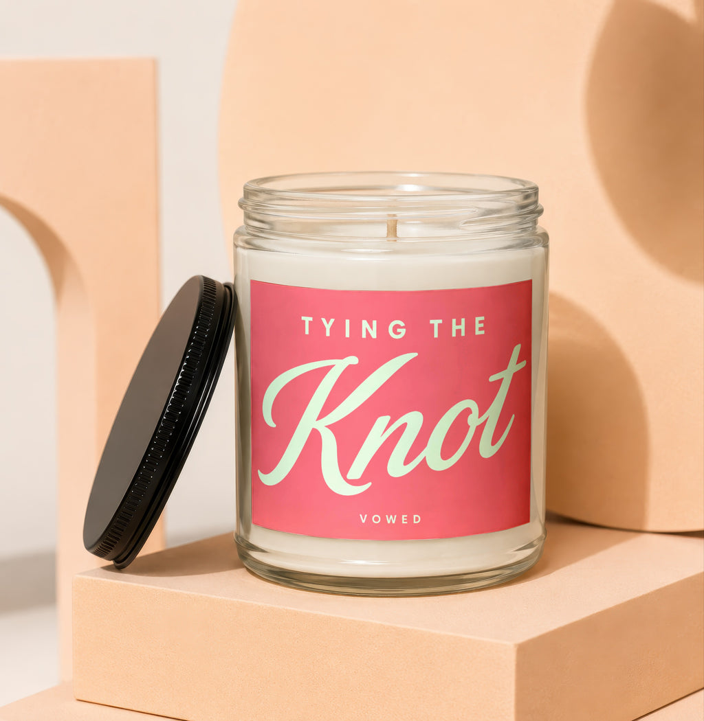 Glass candle with pink label reading "TYING THE KNOT" and "VOWED".