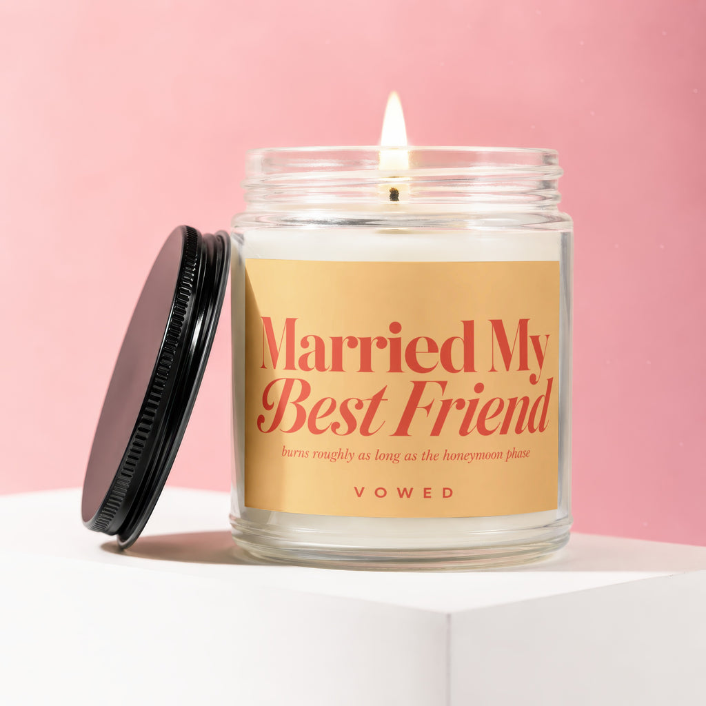 Lit candle in glass jar with "Married My Best Friend" label on pink background.
