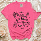 Pink t-shirt with "Holding Her Dress and Her Secrets" text and illustrations.