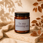 Brown glass candle with black lid, label reads "In my planning era. VOWED."