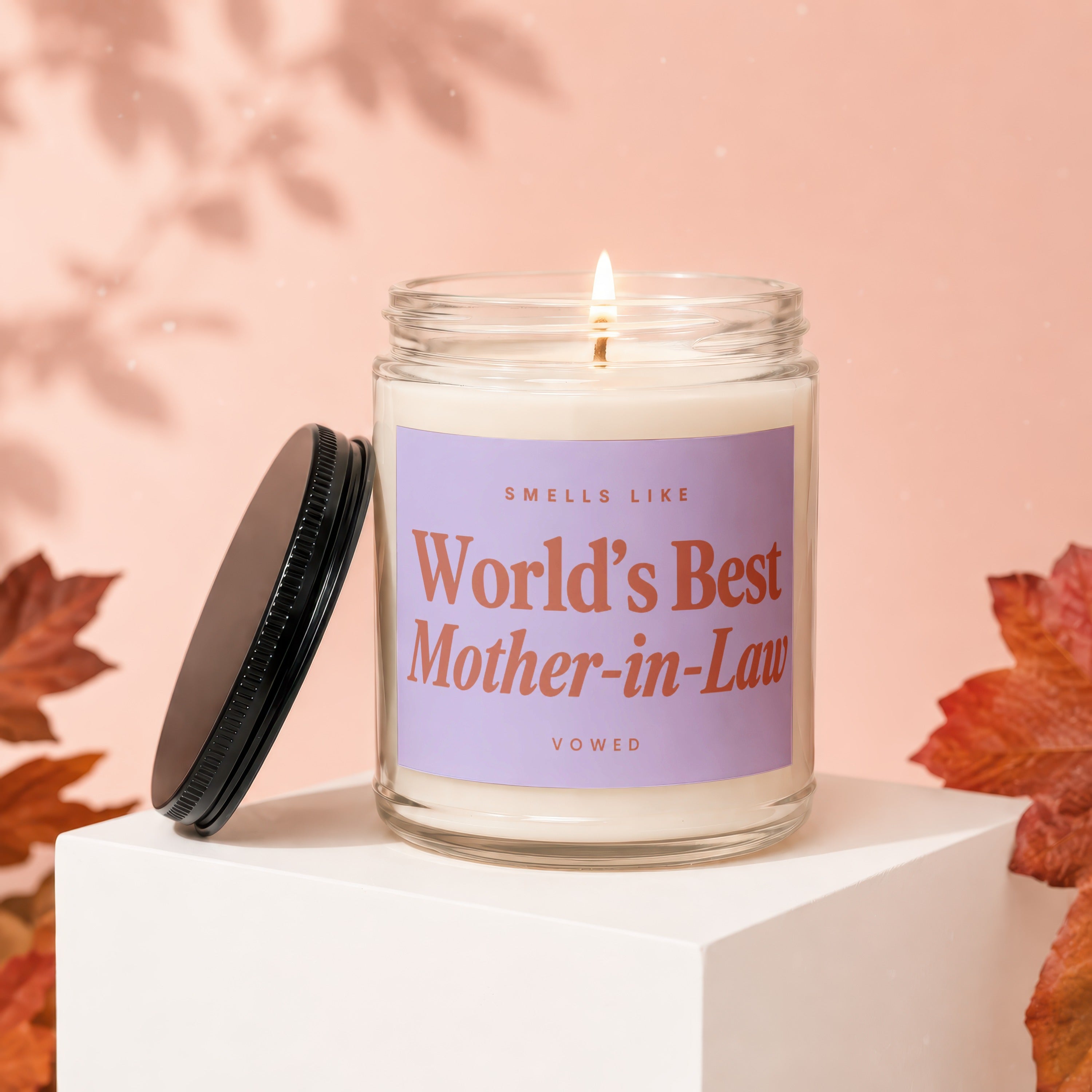 Glass candle with lid off, reading "Smells Like World's Best Mother-in-Law".