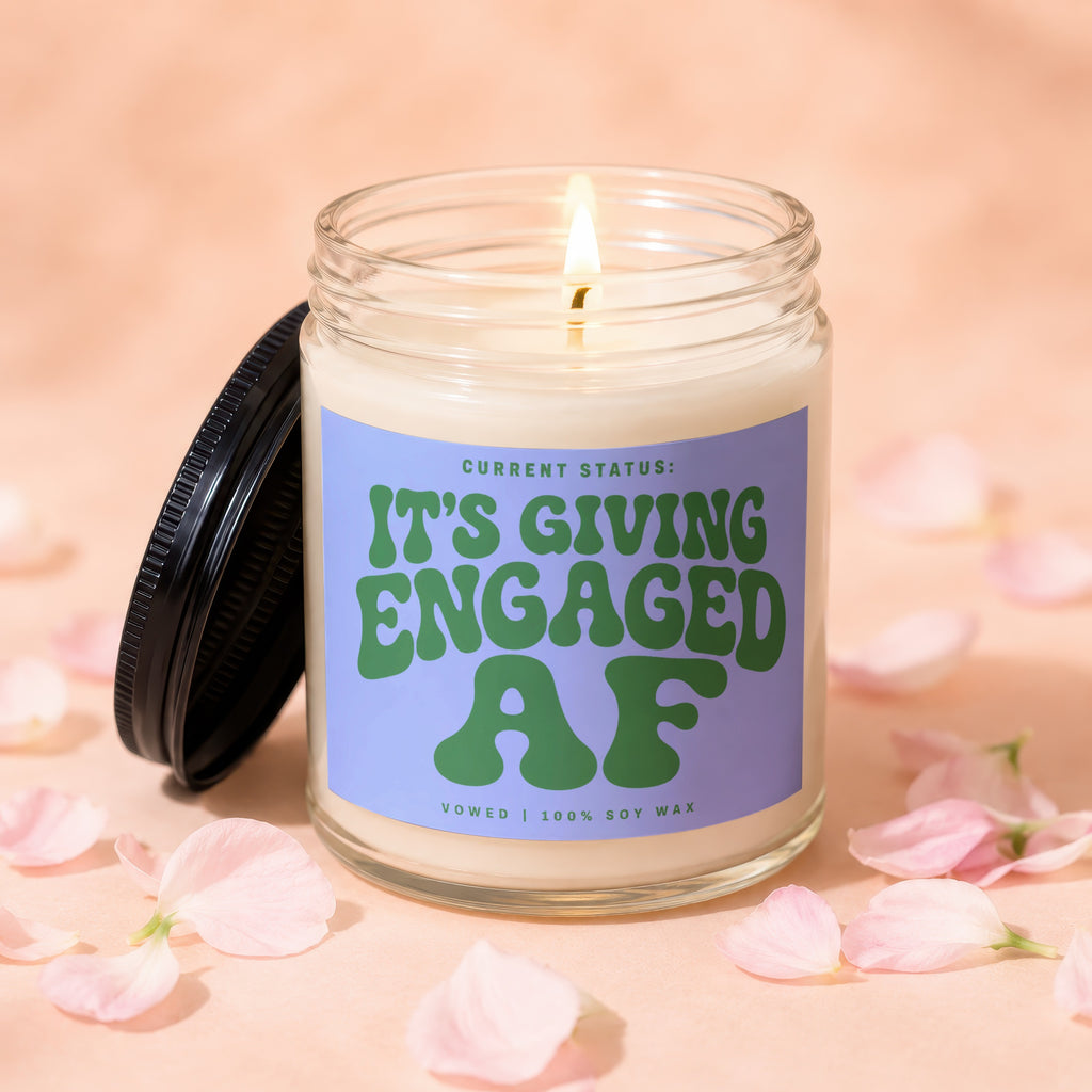 Candle with "It's Giving Engaged AF" text, burning flame and lid.