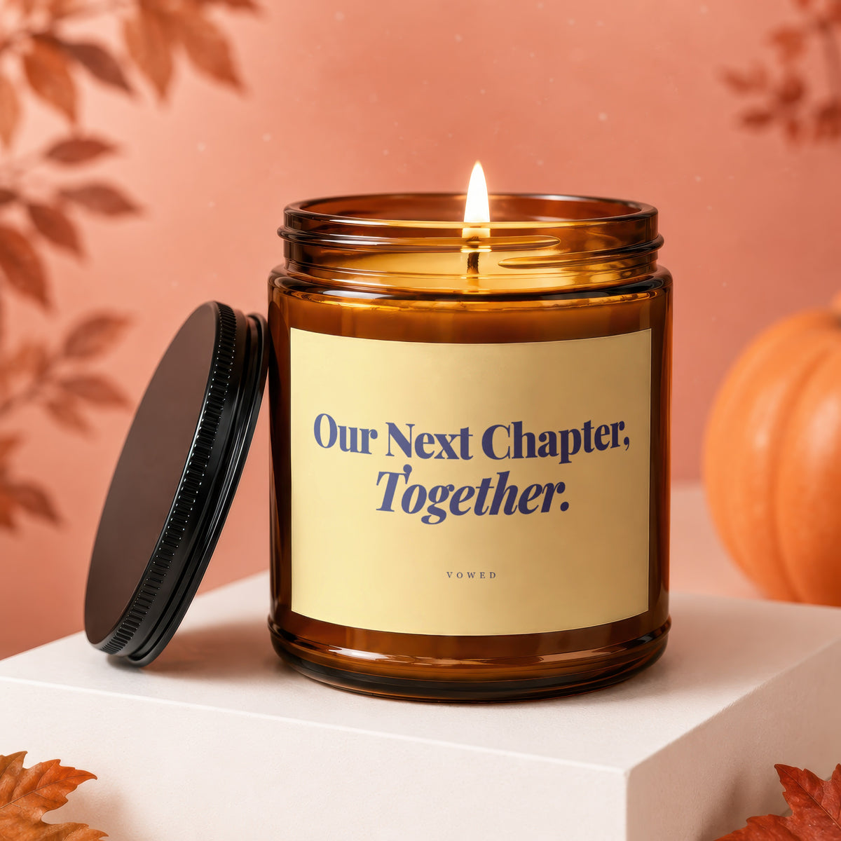 Amber jar candle with lit flame, reads "Our Next Chapter, Together."