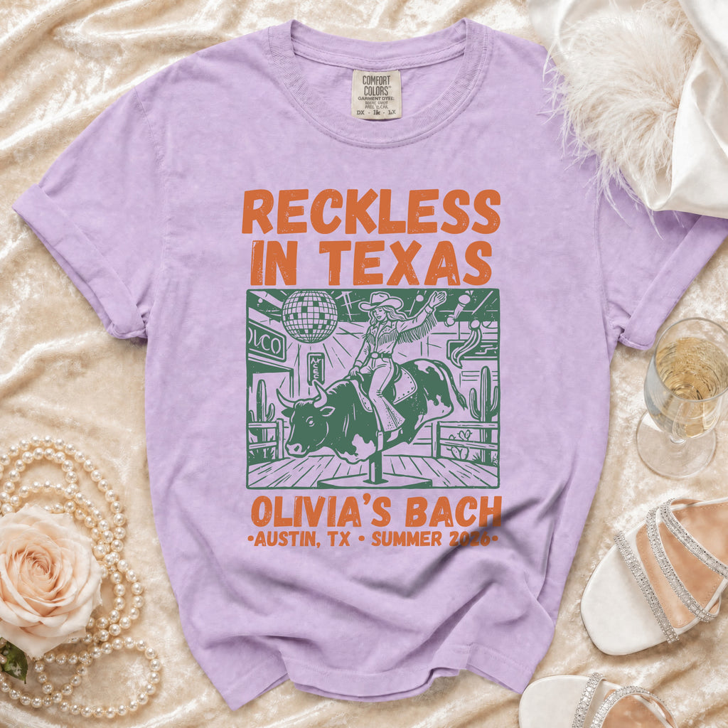 Purple t-shirt with "Reckless in Texas Olivia's Bach Austin, TX Summer 2026" graphic.